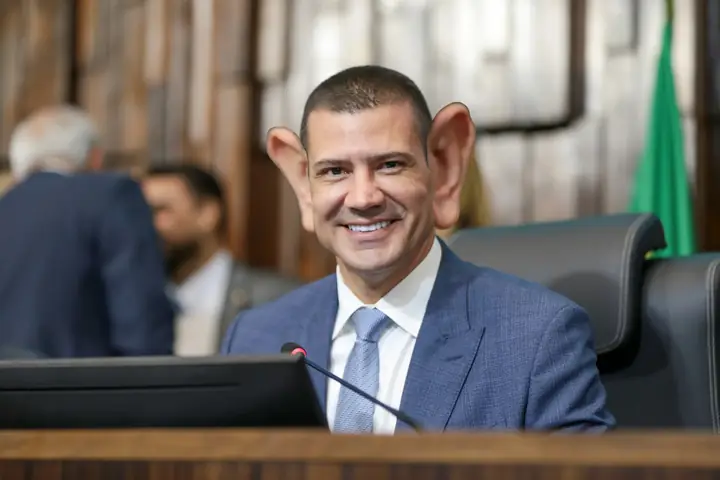Montagem: político sorrindo no plenário, com orelhas gigantes.